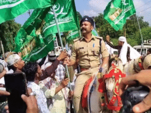 Read more about the article ईद मिलाद उन नबी जुलूस में घोड़े पर बैठे पुलिस अधिकारी हाथ में धार्मिक झंडा लिए नजर आए, SP ने मांगा जवाब; एसडीओपी बोले— “सिर्फ सुरक्षा का निरीक्षण कर रहा था, झंडा किसी ने पकड़ा दिया”!